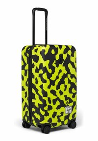 Valise rigide avec un motif abstrait noir et jaune fluo, quatre roues pivotantes et une poignée télescopique noire extensible.