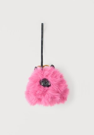 Pink fluffy keychain with black monster face, small ears, and sharp teeth, attached to a black strap.