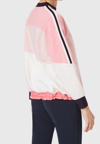 Veste bomber color-blockée en rose, blanc et bleu marine. Comprend une taille élastique, des détails brodés et des rayures bicolores le long des manches.
