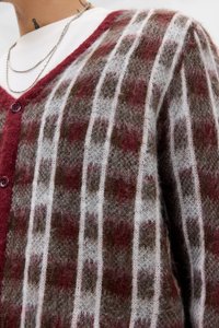 Strikket cardigan med rutete mønster i brunt, rødt og hvitt. V-hals design med knappelukking og myk, fluffy tekstur.