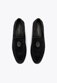 Czarne loafersy wykonane z gładkiego zamszu, z ozdobnym czarnym koralikowym akcentem na górze. Miękka, wyściółkowana podszewka z widocznym logo marki.