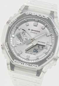 G-SHOCK watch with a clear plastic case, silver dial, analog and digital display, textured accents, and a resin strap. Water-resistant to 20 bar.