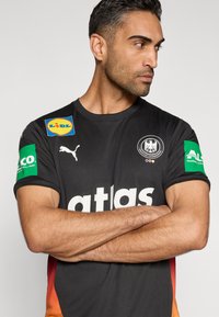 Black athletic jersey with "atlas" in bold white at the front. Features colorful sponsor logos on sleeves and a gradient red to orange side design.