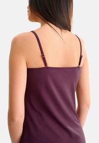 Paarse camisole met dunne bandjes, voorzien van hardware in goudkleur en een gladde, zachte textuur. Van achteren weergegeven, met een ontspannen pasvorm.