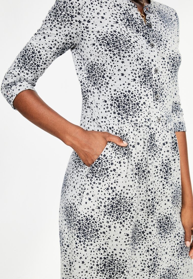 Szara sukienka z rozsypanym granatowym wzorem gwiazd, zapinana na guziki, z rękawami o długości trzech ćwiartek. Posiada boczne kieszenie i dopasowaną talię.