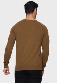 Brun strikket sweater med lange ærmer, ribbede manchetter og kant, samt rund hals. Glat tekstur, tætsiddende design og ingen synlige mønstre.
