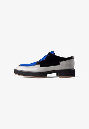 Instap schoenen met een bovenkant van blauwe suède, zwarte accenten en een glanzende witte leren basis. Dikke zwarte zool met een subtiele bruine detail.