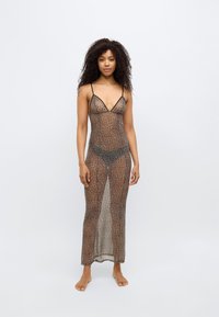 Διαφανές φόρεμα με μοτίβο λεοπάρ, με λεπτές μαύρες τιράντες· μακρύ μέχρι το πάτωμα, ελαφρύ ύφασμα με απαλή υφή και αντιθετικά διαφανή σχέδια.