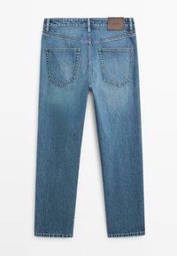 Vue de dos d'un jean en denim bleu avec deux poches arrière et un patch de marque en cuir marron sur la ceinture.