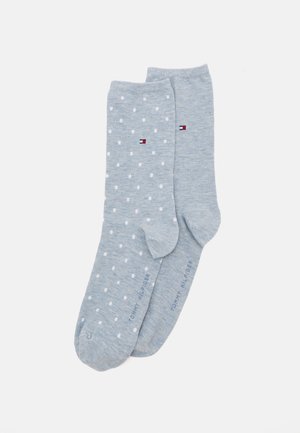 Lichtblauwe sokken van zacht materiaal, met witte stippen op één sok, en het merkembleem in rood, wit en blauw op beide.