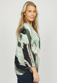 Langærmet bluse med et akvarelmønster i mint, sort og blød lyserød, der har en afslappet pasform og samlede manchetter for ekstra detalje.