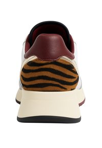 Sneaker bianca con tallone in pelle bordeaux e dettaglio in pelliccia sintetica marrone a strisce nere sul tallone. Suola piatta in gomma beige.