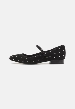 Black suede flat shoe with a rounded toe, ankle strap, and decorative silver studs across the upper. Low, block heel design.
