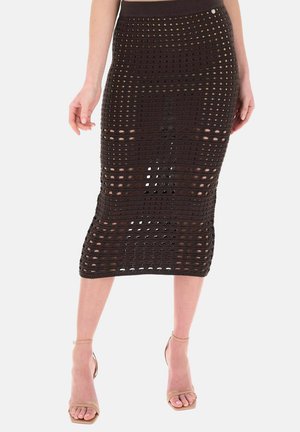 Gonna midi nera all'uncinetto con motivo a quadrati aperti, indossata con sandali nude con cinturino alla caviglia e tacco alto, mostrata dalla vita a metà polpaccio.