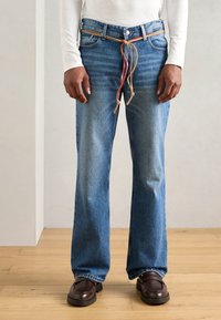 Hellblaue Denim-Jeans mit geradem Schnitt, ausgestattet mit einem gewebten, mehrfarbigen Kordelzuggürtel und einem Fünf-Taschen-Design. Strukturiertes Material, minimaler Verblassungsgrad.