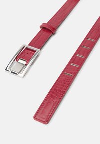 Cinto de imitação de couro vermelho com um padrão texturizado semelhante ao de crocodilo. Fivela quadrada prateada com garra, apresentando furos uniformemente espaçados.