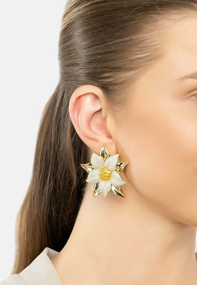 Gold and silver floral-shaped earring featuring textured petals, a central yellow bead, and pointed accents. Adjustable stud backing visible.