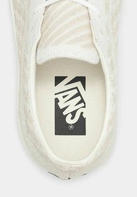 Hvide Vans sneakers med tekstureret overdel, prydet med et mønsterdesign. Indersiden viser et sort Vans-logo på en cremet indersål. Klassisk snørebåndslukning.