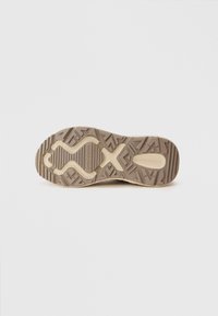 Semelle de chaussure de sport avec une surface en caoutchouc beige texturé, dotée d'un motif de bande de roulement géométrique et de rainures pour une meilleure adhérence et flexibilité.