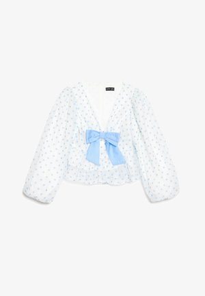 Bela bluza z dolgimi rokavi z nežno modrimi pikami, globokim V-izrezom, napihnjenimi rokavi in velikim svetlo modrim trakom spredaj na sredini.