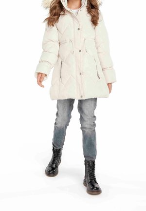 Pufet hvid jakke med diamantmønster, frontlynlås og hætte foret med pels, parret med smalle blå jeans og sorte snørebåndsstøvler.