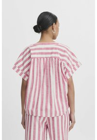 Top a maniche corte a righe rosa e bianche con dettaglio plissettato sul retro. Tessuto leggero, vestibilità leggermente ampia, scollatura arrotondata. Design casual.