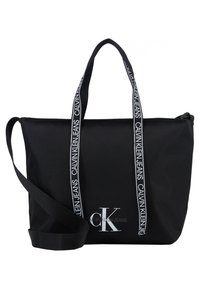 Czarny torba tote marki Calvin Klein z białym logo z przodu, podwójnymi uchwytami z powtarzającym się tekstem oraz regulowanym paskiem na ramię.