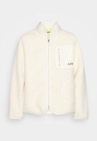 Kremowa kurtka polarowa z wysokim kołnierzem, okrągłymi kieszeniami bocznymi, kieszenią na zamek na piersi oraz szarym detalem z logo na przodzie.