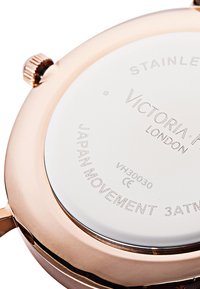 Reloj de acero inoxidable color oro rosa con la parte posterior grabada. Superficie de cristal blanco, forma circular y una corona plateada en el lateral.