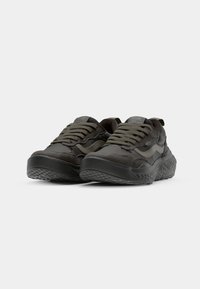 Black sneakers with a textured rubber sole, featuring a mix of smooth and suede panels, and matching lace-up design.