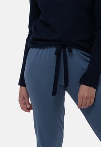 Marinblus med långa ärmar i kombination med ljusblå joggingbyxor med snörning. Byxorna har en mjuk känsla, elastisk midja och en avslappnad passform.