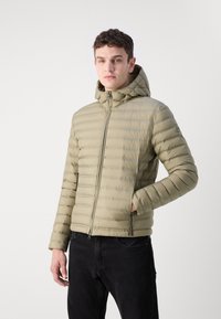 Svetlo oliivno zelena pufasta jakna s kapuco, z vodoravnimi prešitimi sekcijami, zadrgo in dvema stranskima žepoma; gladka, vodoodporna tkanina.