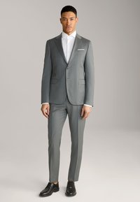 Grau Anzug mit taillierter Passform, einreihiger Blazer, Reverskragen und zwei Seitentaschen, kombiniert mit einem weißen Hemd und schwarzen Schuhen.