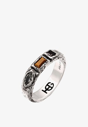 Bague texturée en argent avec trois pierres précieuses : ovale noire, ambre rectangulaire et carré violet foncé, gravée avec "JG 925" à l’intérieur de l’anneau.