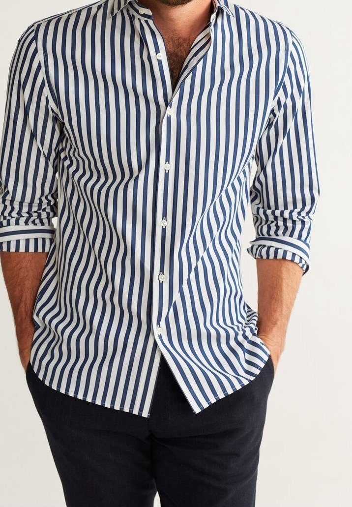 Camicia a righe in navy e bianco. Presenta una chiusura con bottoni sul davanti, maniche lunghe e colletto a punte, con una forma aderente e una texture liscia.