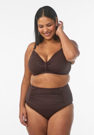 Smiling woman with shoulder-length black hair wearing a brown ruched bikini top and high-waisted bottoms against a white background.