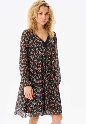Robe noire à fleurs avec des manches longues, décolleté en V, et jupe froncée. Présente de petites fleurs roses et blanches, faite de tissu léger et semi-transparent.