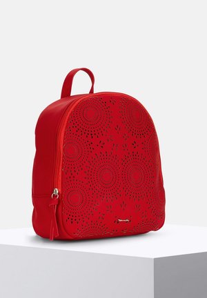 Sac à dos en cuir rouge avec un motif floral découpé au laser, de forme arrondie, muni d'une poignée supérieure et d'une fermeture à glissière. Fini texturé avec des coutures visibles.