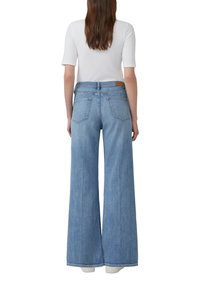 Jeans blu a gamba larga, denim chiaro, cinque tasche, vita alta, passanti per cintura e una toppa in pelle marrone sul retro.