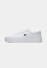 Sneaker de couro branco com uma textura suave, bico arredondado, atacadores planos e sola de borracha. Apresenta um pequeno logótipo dourado na lateral.
