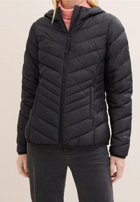 Černá prošívaná péřová bunda se vzorem rybí kostry, zapínáním na zip a kapucí. Měkký, lehký materiál s přiléhavým střihem.