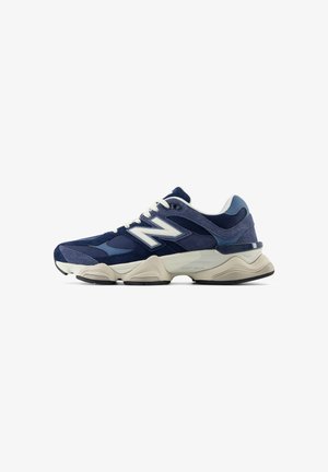 Baskets pour homme New Balance bleu marine et bleu avec lacets blancs, logo blanc, dessus en mesh et daim, et semelle épaisse beige sur fond blanc.