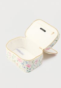 Kukkakuvioinen kosmetiikkalaukku, jossa on kermaan vivahtava pohja, kultainen vetoketju ja vuorattu sisäosa vetoketjullisella taskulla.