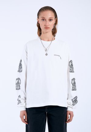 Weißes langärmliges T-Shirt aus Baumwolle, mit schwarzen dekorativen Drucken auf den Ärmeln und einem kleinen Logo auf der Brust.