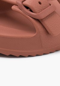 Sandalo in gomma marrone con superficie texturizzata, suola spessa, cinturino regolabile e una soletta sagomata per comfort e supporto.