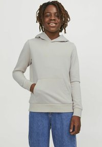 Hoodie grigio chiaro realizzato in tessuto morbido, con tasca anteriore a marsupio, cappuccio con cordino e polsini a coste. Indossato con pantaloni corti di jeans blu.