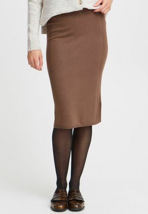 Neulepintainen ruskea kynähame, jossa on pystyribbaus, polvimittainen, yhdistetty mustiin sukkahousuihin ja ruskeisiin fringed loafer-kenkiin.