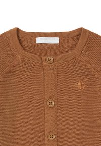 Brun stickad cardigan med rund halsringning, tre knappar fram och en liten broderad logotyp på bröstet.