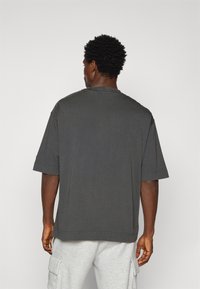 Grå oversized t-skjorte med korte ermer, rund hals og myk tekstur. Enkelt design uten synlige mønstre eller detaljer.