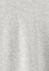 Tessuto grigio chiaro con una texture a maglia fine, caratterizzato da un motivo uniforme e una finitura liscia, adatto per abbigliamento casual o per essere indossato a strati.